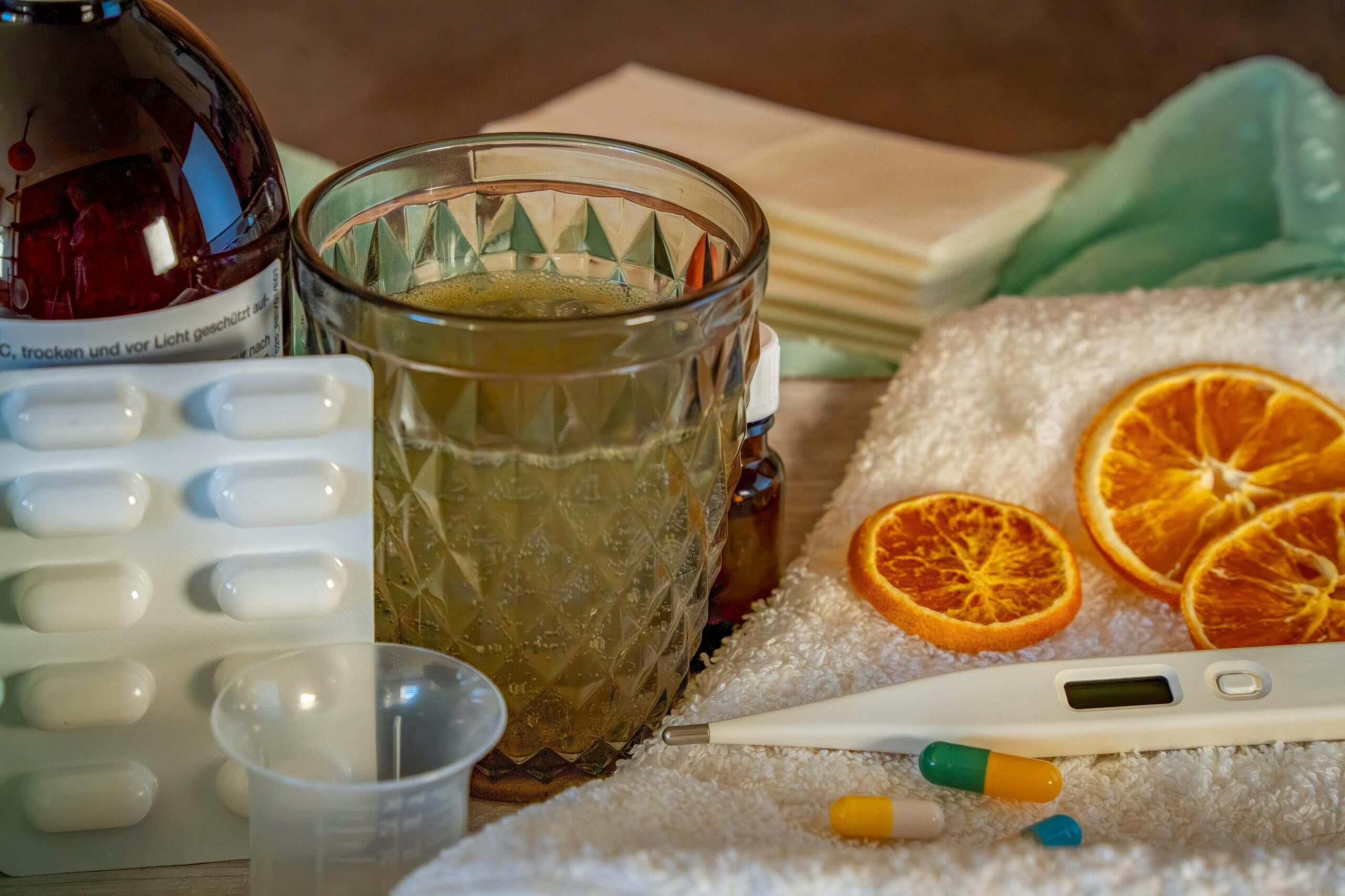 A collection of home remedies and medications for treating cold and flu symptoms, including a thermometer, pills, and herbal tea.