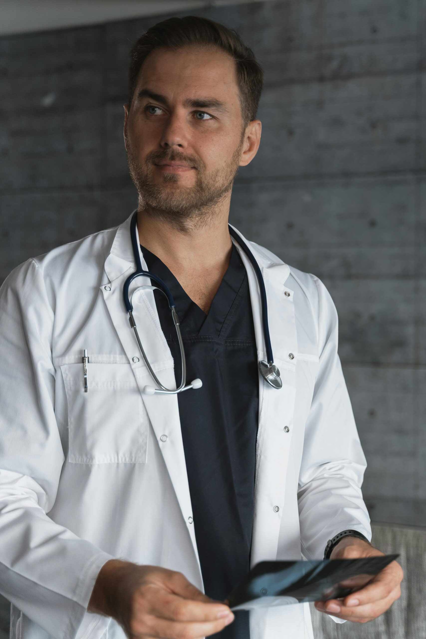 Confident male doctor in white lab coat analyzing an x-ray image indoors.