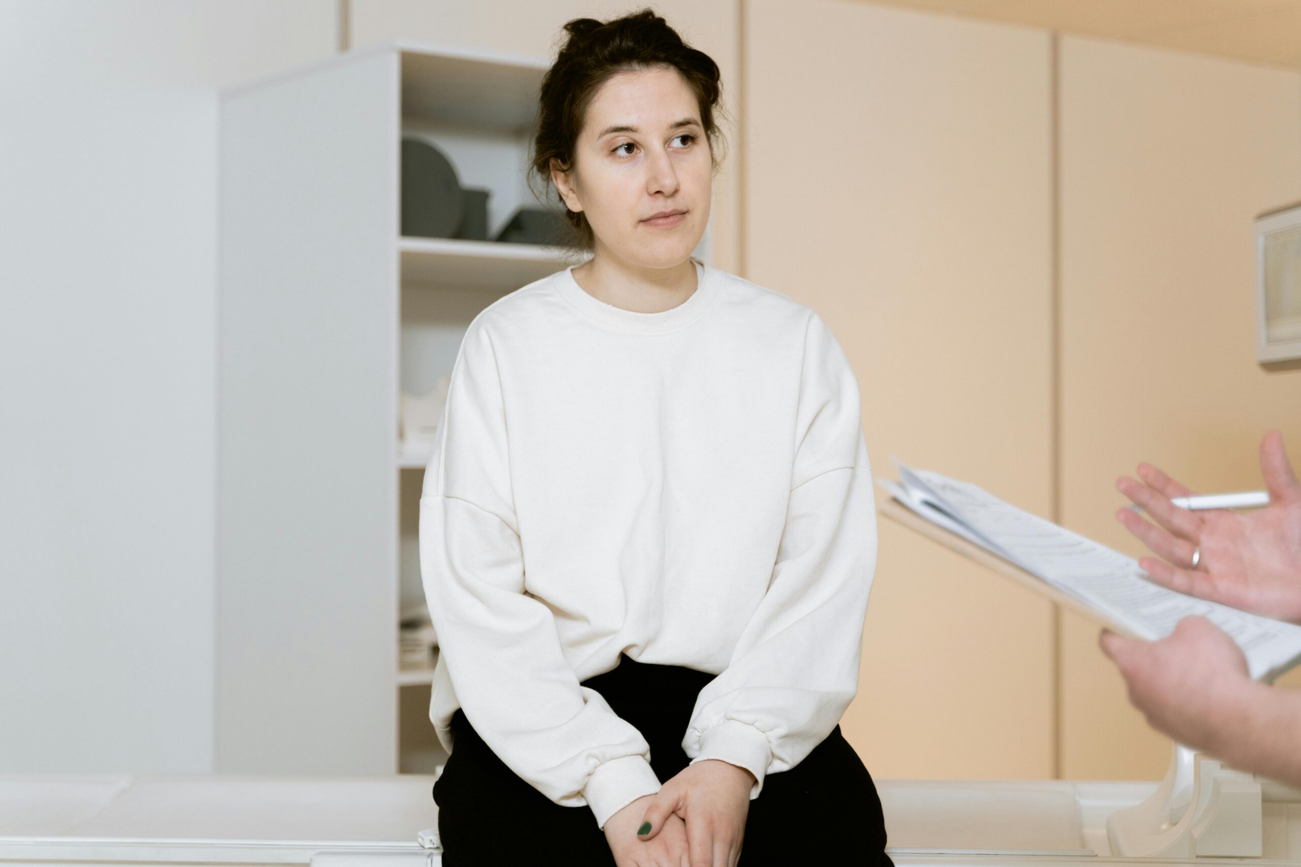 Adult woman sitting attentively during a medical consultation inside a clinic.