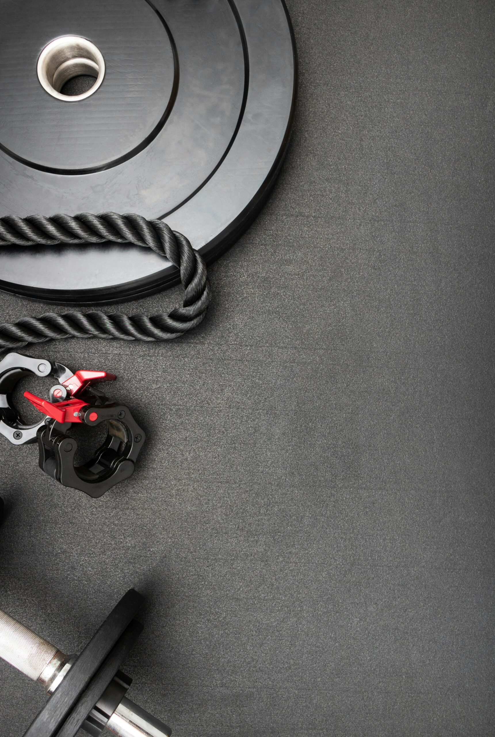 A composition of gym equipment including weights, rope, and clamps on a dark background. Perfect for fitness themes.