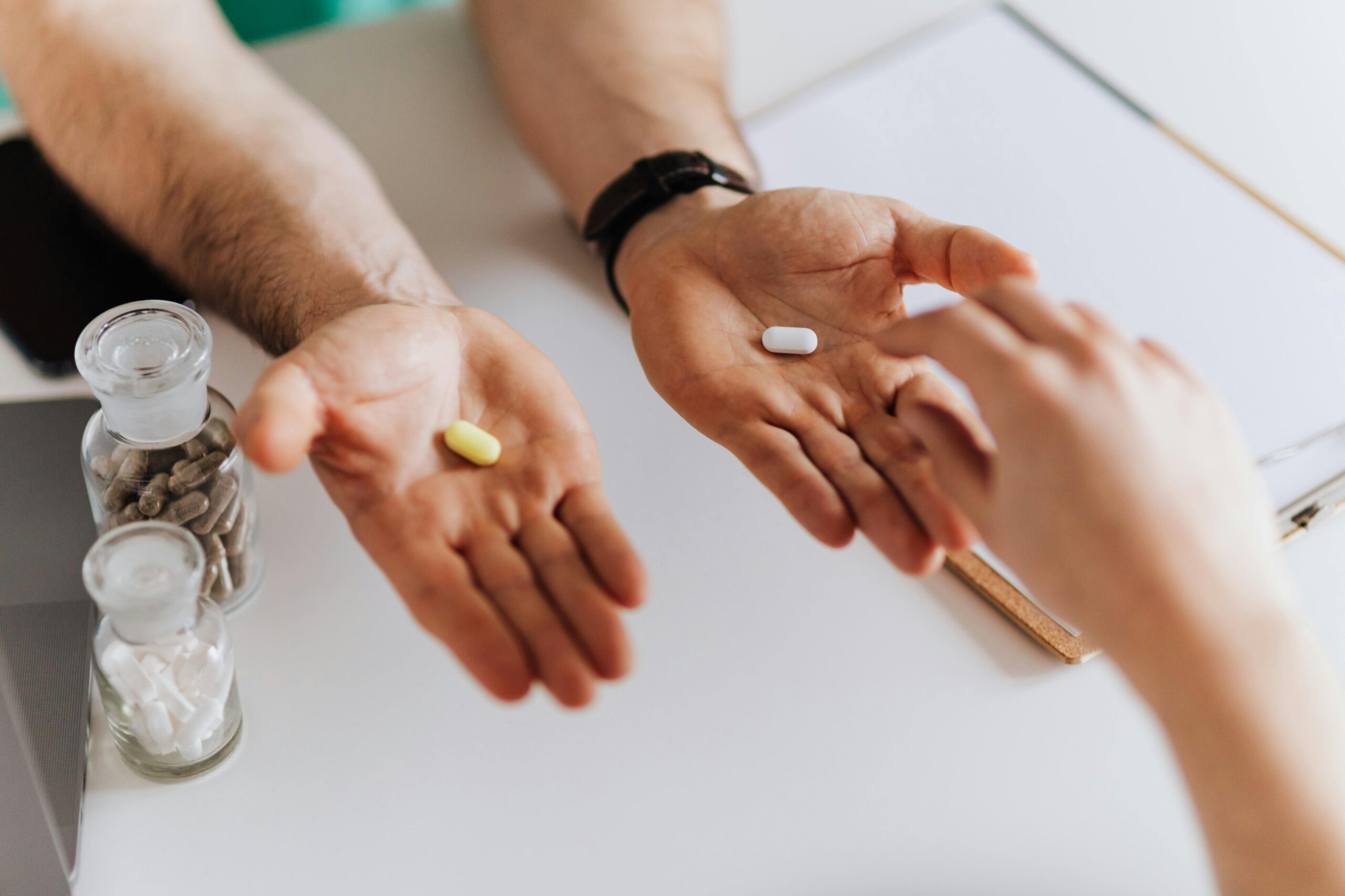 From above anonymous female and unrecognizable doctor man giving yellow and white tablets for choosing while working in modern clinic