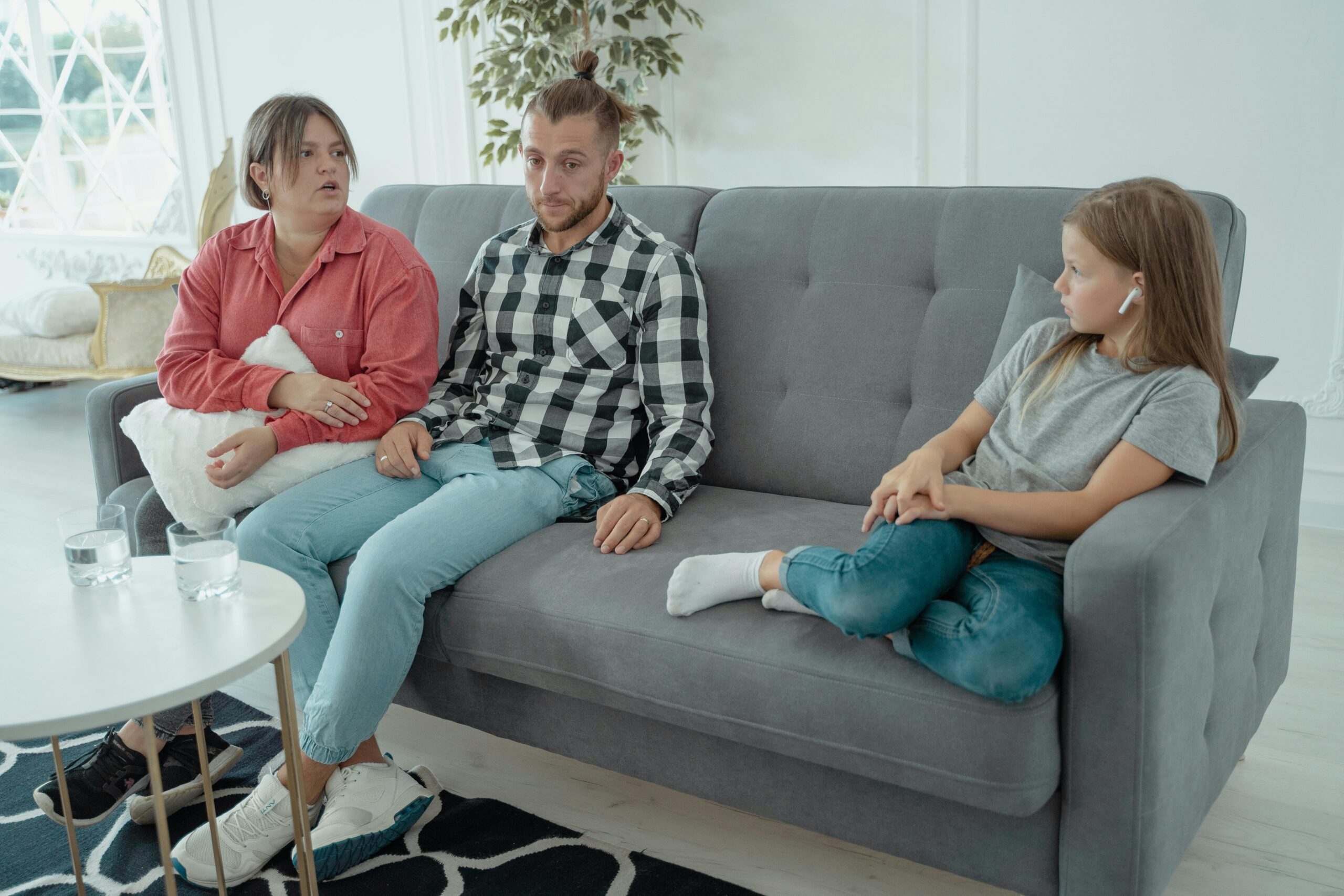 A family sits together on a sofa, discussing in a comfortable home setting, indicating a counseling session.