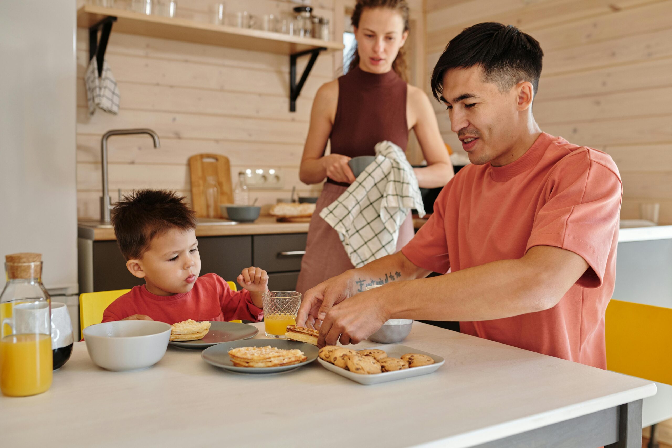 A family shares a breakfast meal in a cozy kitchen setting, emphasizing togetherness.