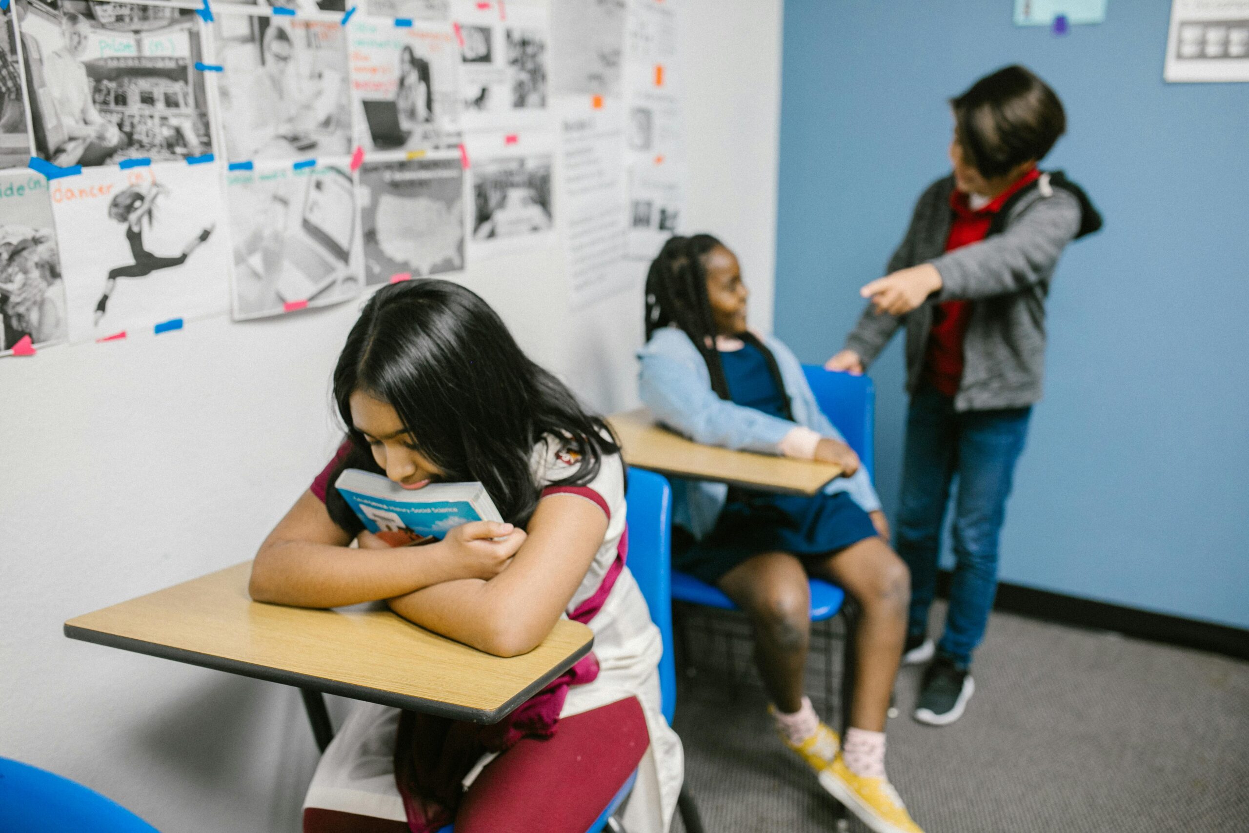 A sad girl in a classroom being bullied by classmates, highlighting anti-bullying awareness.