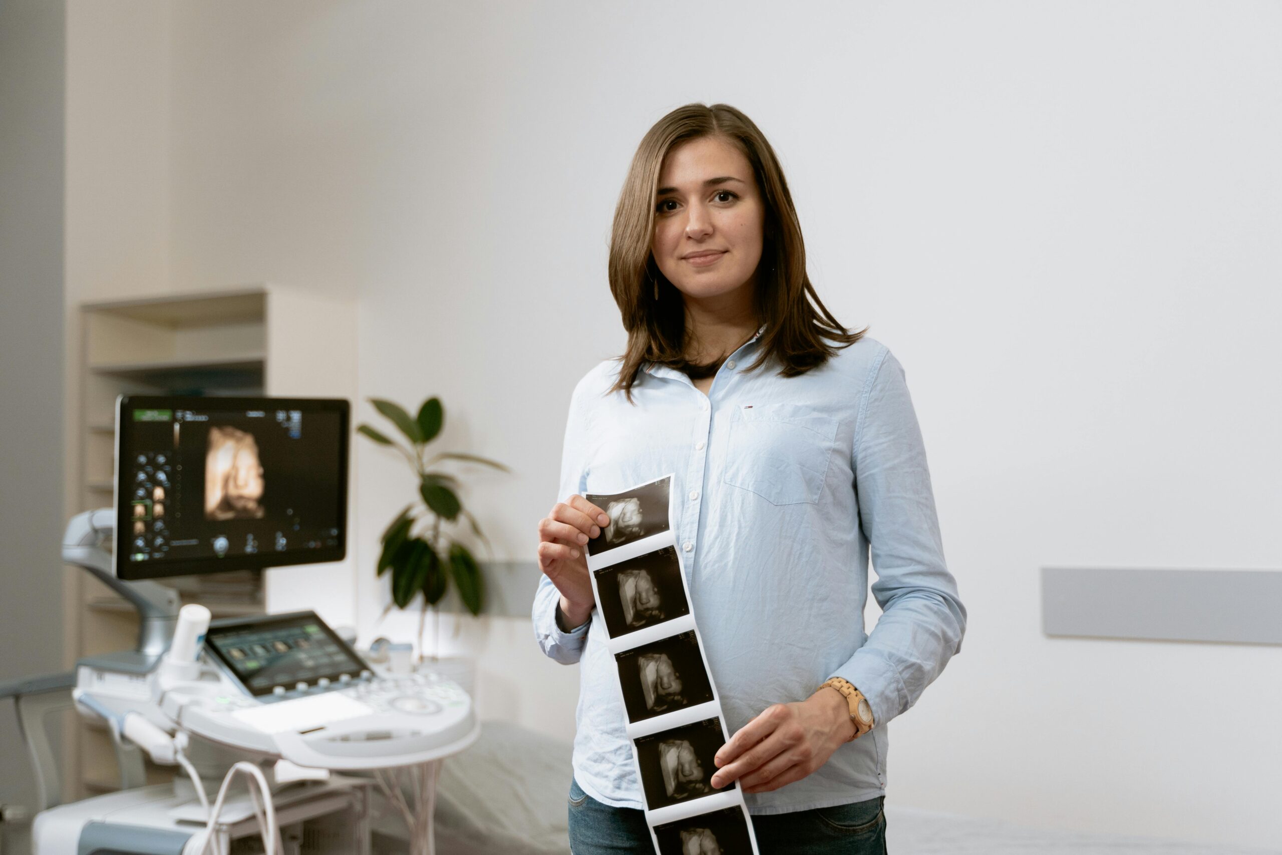 Expectant mother showing ultrasound images in a modern healthcare clinic setting.