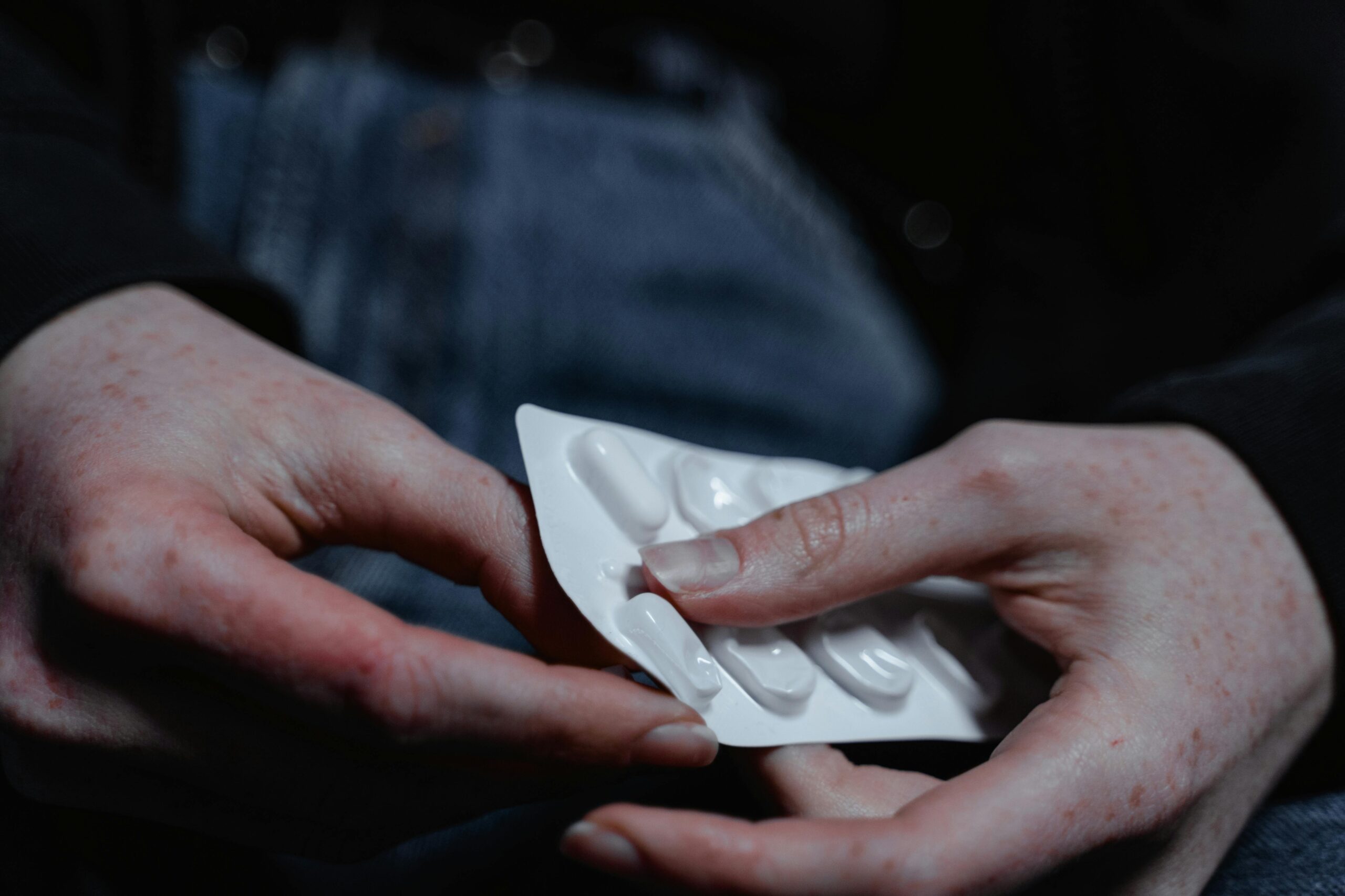 Person holding a blister pack of medication, highlighting health and treatment themes.