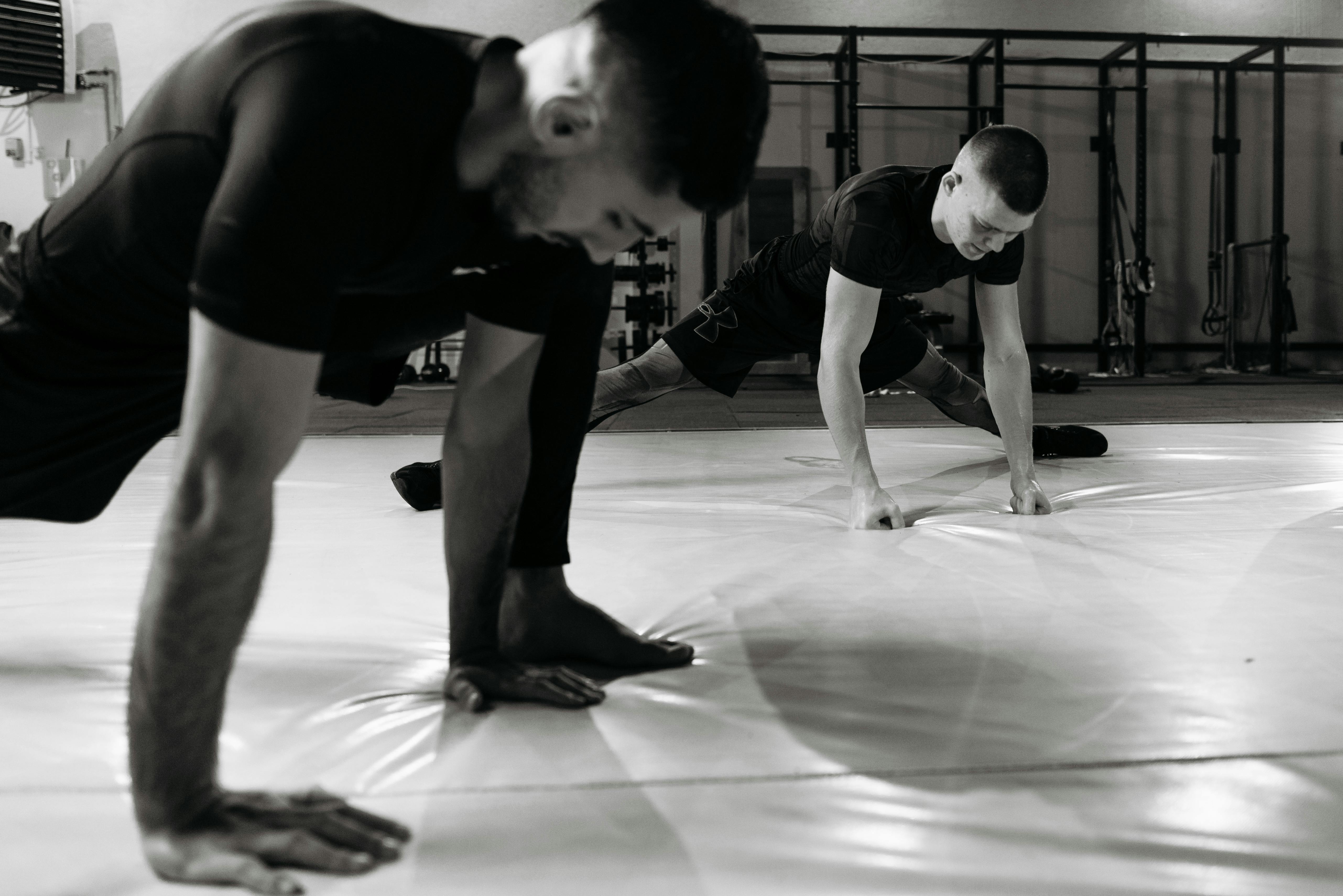 Two men stretching and warming up in a gym, preparing for a workout session.