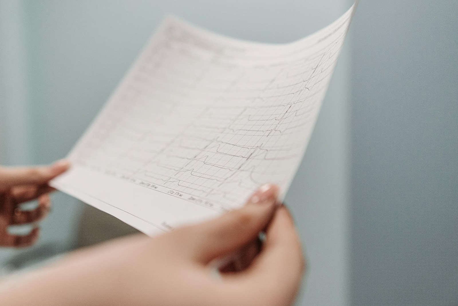 Close-up of a person holding an ECG printout, symbolizing medical diagnosis and health analysis.