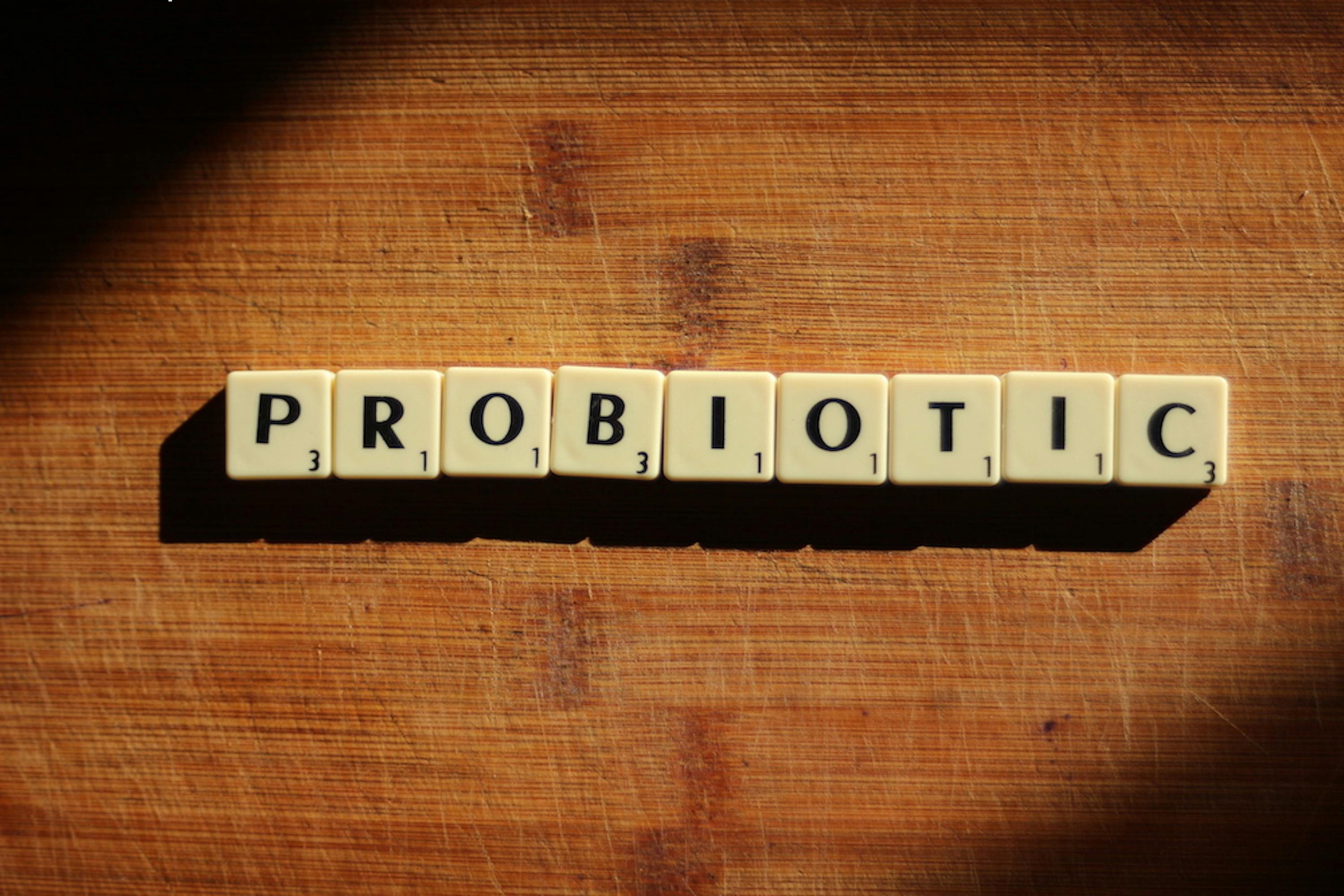 Close-up of the word 'probiotic' crafted from letter tiles on a wooden surface.