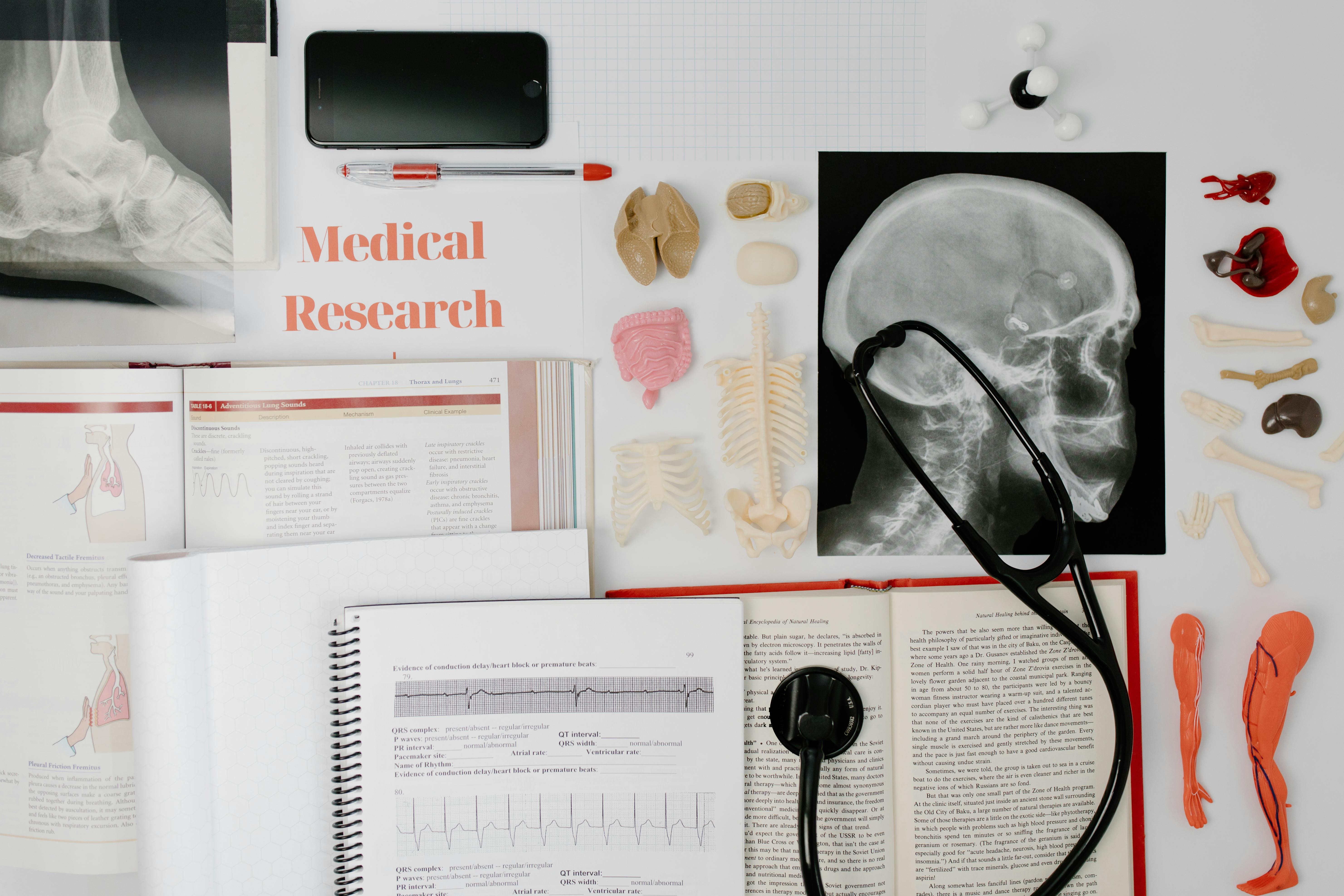 Overhead view of medical research equipment and study materials including books, x-rays, and stethoscope.