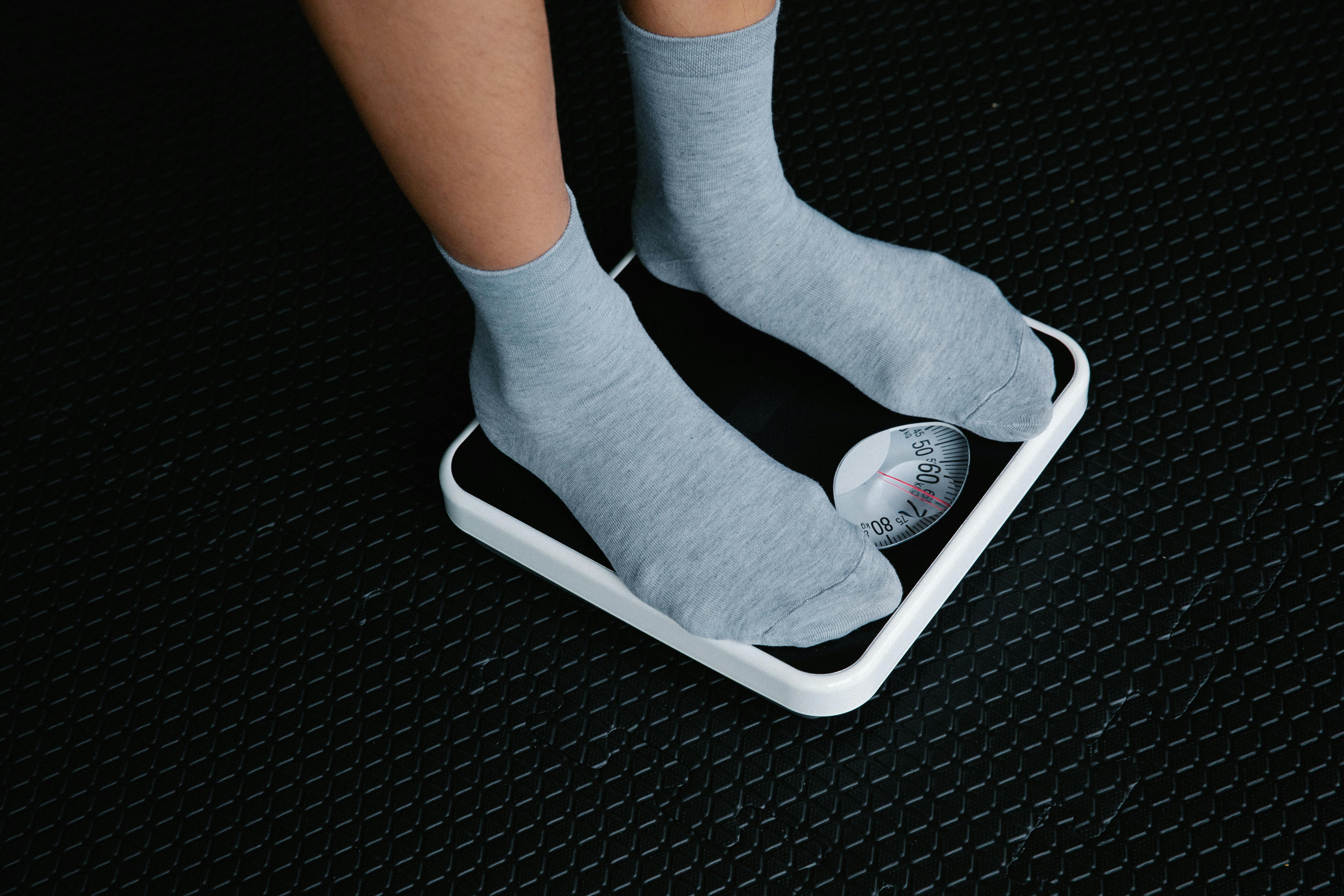 Close-up of feet in socks standing on a scale, focusing on weight measurement.